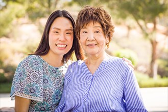 Outdoor portrait of a happy chinese mother and daughter