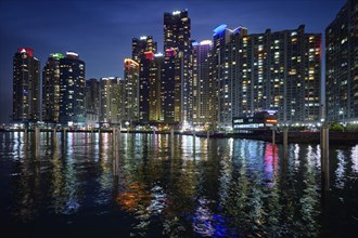 Busan Marina city skyscrapers illluminated in night with reflection in water, South Korea, Asia