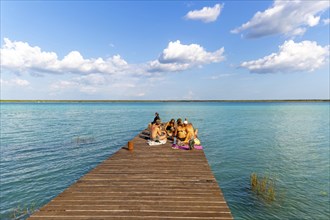 People sitting on woooden jetty pier by waterside, Lake Bacalar, Bacalar, Quintana Roo, Yucatan