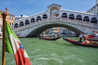 Italian maritime flag with Rialto bridge with boats and gondolas in the bacground. Grand Canal,