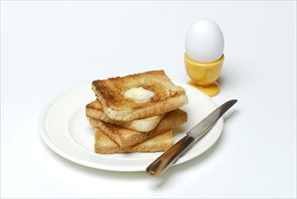 Toast, melting butter, breakfast egg, toast, plate, knife, egg cup, egg