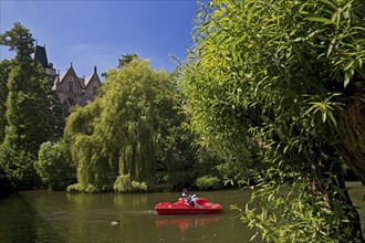 Father and son in a pedal boat on the river Lahn with the Old University in the background,