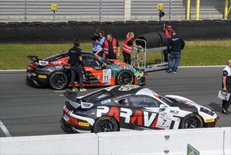 Team manager of car racing team and mechanic with spare tyres next to racing car Sports car Porsche