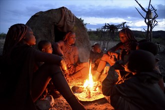 Himba women sitting around a fire in the early morning, Ombombo, Kaokoland, Kunene, Namibia, Africa