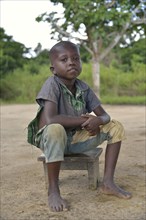 Boy sitting on a stool, Nkala, Bandundu Province, Democratic Republic of the Congo