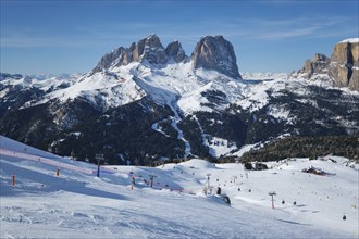 View of a ski resort piste with people skiing in Dolomites in Italy. Ski area Belvedere. Canazei,