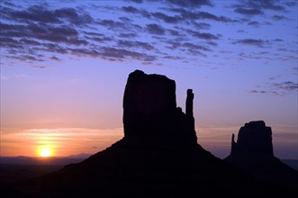 Eroded sandstone rock formations, buttes the Mittens silhouette at dawn in Monument Valley Navajo