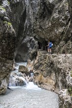 Hiker in a gorge, Hammersbach flows through Höllentalklamm, near Garmisch-Partenkirchen,