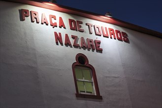 Illuminated façade with inscription, Praça de Touros da Nazaré, bullring, night shot, Portugal,