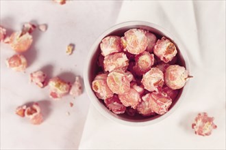 Top view of pink colored strawberry flavored sweet popcorn in white bowl