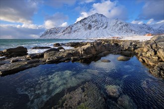 Beach of Norwegian sea on rocky coast in fjord on sunset in winter. Vareid beach, Lofoten islands,