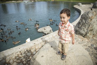 Young chinese and caucasian boy having fun at the park and duck pond