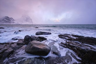 Beach of Norwegian sea on rocky coast in fjord on sunset in winter. Vareid beach, Lofoten islands,