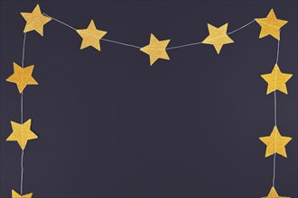 Golden glittering star garland on dark black background with blank copy space