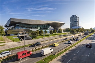 Road traffic in front of BMW Welt and the BMW four-cylinder administration building in Munich,