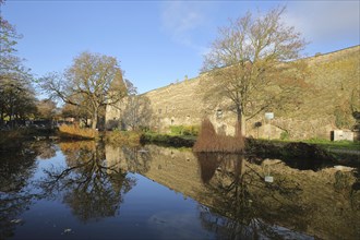 City fortification with historic Dadenberg Tower and reflection in the duck pond during autumn,