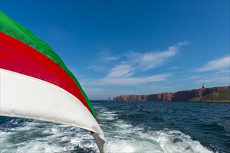 Red red sandstone cliff edge, Heligoland high sea island, Lange Anna, Heligoland flag, North Sea,