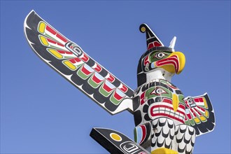 Colourful wooden carved Canadian totem pole showing eagle against blue sky