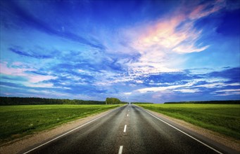 Travel concept background, road and stormy dramatic sky on sunset