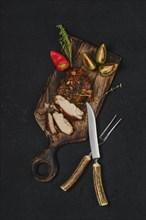 Overhead view of baked in oven pork fillet on wooden serving board