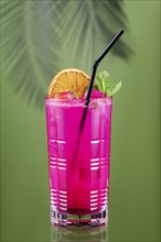 Cold lemonade with dragon fruit, orange and coconut juice on green background