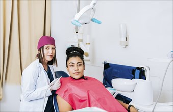 Portrait of young dentist with female patient in medical office, Female dentist with female patient