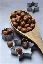 Wooden ladle with hazelnuts, cookie cutters, baking ingredient