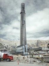 Chimney of the smelter, in the foreground a spoil heap contaminated with heavy metal residues, La