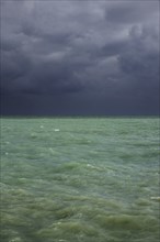 Dark rain clouds over emerald coloured sea water