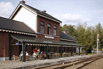 Tourist on pavement café of the old railway station in the Hoge Kempen National Park near As,