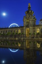 Reflection of the crown gate of the Zwinger and the Ferris wheel in the water basin of the