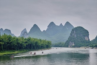 Tourist boats on Li river with dramatic karst mountain landscape in the background. Yangshuo,