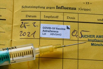 Syringe and vaccination certificate with entry for vaccination with AstraZeneca against Covid-19,