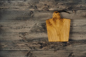 A beautifully crafted wooden cutting board rests on a rustic wooden countertop, showcasing its