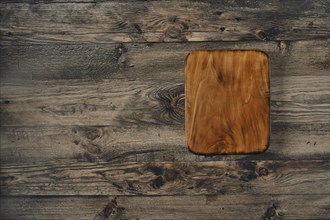 A beautifully crafted wooden cutting board is placed on a rustic wooden table, showcasing its