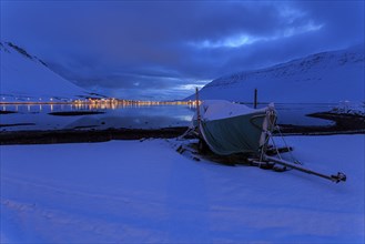 Boat in front of a fjord landscape, twilight, snow, illuminated city, mountains, Isafjördur,