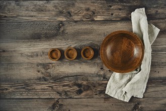 A large wooden bowl sits comfortably surrounded by three smaller bowls on a weathered wooden table.