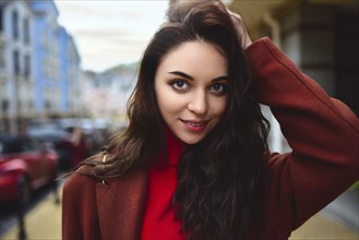 Portrait of a fashionable woman posing for the camera in a brown coat and red sweater