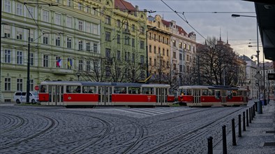 Red historic trams running on cobblestone streets surrounded by old buildings in Prague, with an