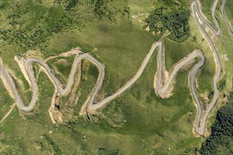 Aerial top view of countryside winding road passing through the green hills and mountain