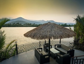 Riverside sunset view in kampot cambodia asia with relaxing deck sofa chairs and table