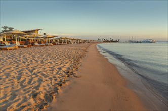 Empty beach with beach loungers and umbrellas at morning. Resort coast without people, Concept of