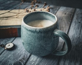 A large coffee cup standing in front of an old book