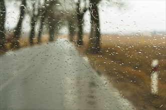 The road is wet from the rain, rain drops on the car glass