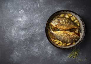 Baked sea bream or dorada with onion and herbs in pan on dark background