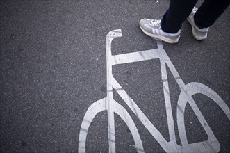 Close-up, shoes, sneakers, pedestrian standing on cycle path, marking, labelling, pictogram,