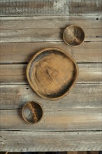 Three wooden bowls in varying sizes are artfully placed on a rustic wooden table, showcasing