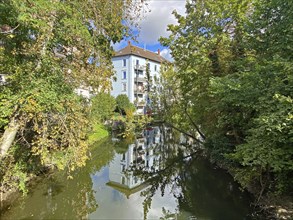 Tranquil natural scene with a river, lined with trees, and a building reflected in the water, Oker,