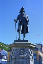 Ludvig Holberg statue on a pedestal in front of historic buildings on a sunny day, Bergen,