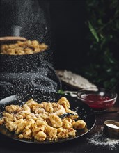 Kaiserschmarrn on a black plate, sprinkled with sugar, dark background